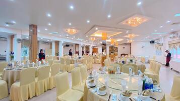 A banquet hall with round tables, chairs, and staff.