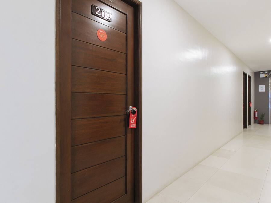 Een hotelgangen met een houten deur waarop '2de Verdieping' staat en een lift in de verte.