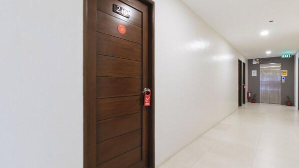 Un pasillo de hotel con una puerta de madera que indica '2do Piso' y un ascensor a lo lejos.