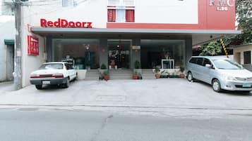 Ein RedDoorz-Gebäude mit zwei geparkten Autos davor.
