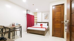 A hotel room with a bed, a desk with a chair, a telephone, and a door. - Reddoorz Near Fernwoods Garden Quezon City (Quezon City)