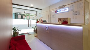 A reception area with a RedDoorz sign, a tip box, a suggestion box, and a 'Be Safe' notice. - Reddoorz Near Fernwoods Garden Quezon City (Quezon City)