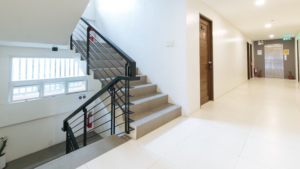 A modern hotel interior with a staircase, a fire extinguisher, and an elevator. - Reddoorz Near Fernwoods Garden Quezon City (Quezon City)