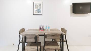 A dining area with a wooden table, four chairs, two water bottles, and a framed picture on the wall.