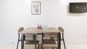 Un comedor con una mesa de madera, cuatro sillas, dos botellas de agua y un cuadro en la pared.