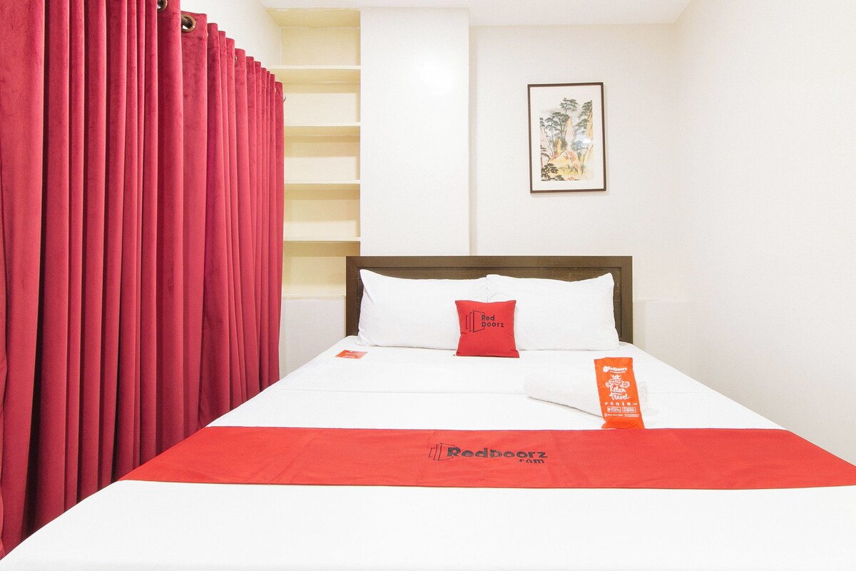 A hotel room with a bed, a red curtain, a framed picture on the wall, and a red pillow with the Red Doorz logo.