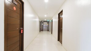 Un pasillo de hotel con puertas de madera, piso de baldosas y una señal de salida.