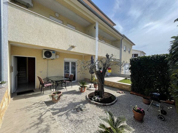 A building with a patio area featuring a table and chairs, potted plants, and a barbecue grill. - Apartment Malu is located in a quiet neighborhood in Pula. (Pula)