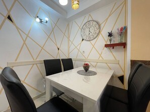 A dining area with a white table, black chairs, a wall clock, and a decorative shelf with flowers. - Apartment Malu is located in a quiet neighborhood in Pula. (Pula)
