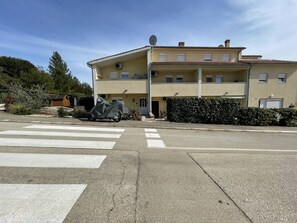 A two-story building with a flat roof, a satellite dish, and a covered motorcycle. - Apartment Malu is located in a quiet neighborhood in Pula. (Pula)