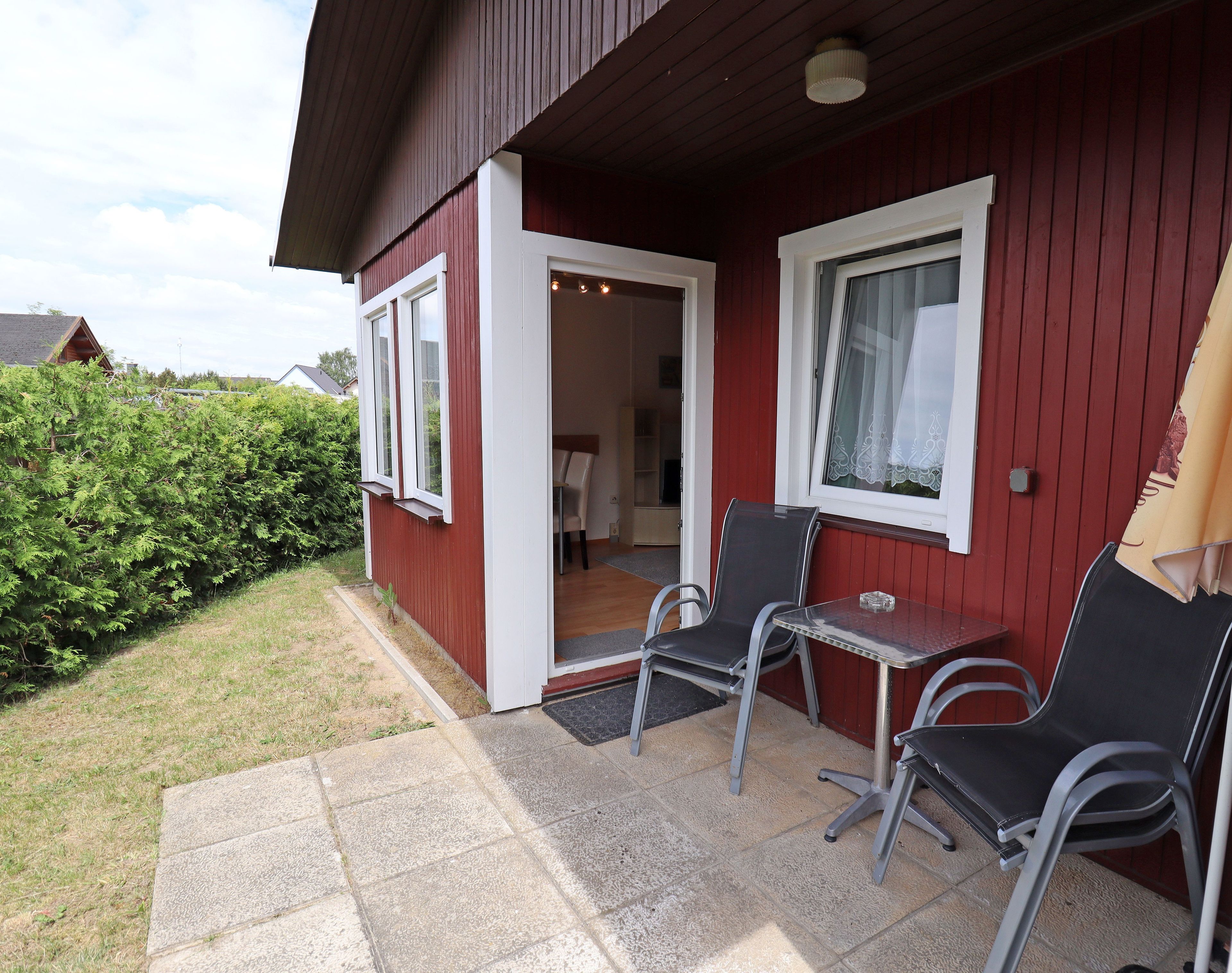 Ein rotes Gebäude mit einer Terrasse, auf der zwei Stühle und ein kleiner Tisch stehen.