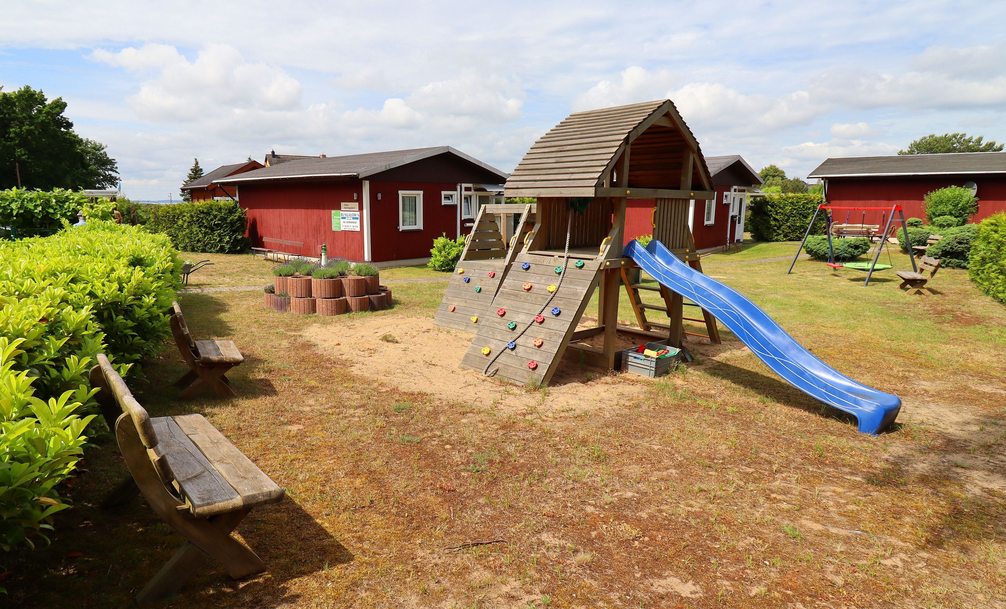 Une aire de jeux avec un toboggan, un mur d’escalade et des balançoires.