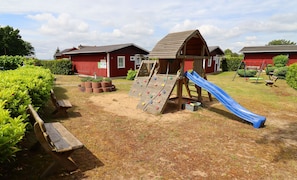 A playground with a slide, climbing wall, and swings. - TUI Haus Ahlbeck - Räuberkuhle 1 Vacation Homes (Koserow)
