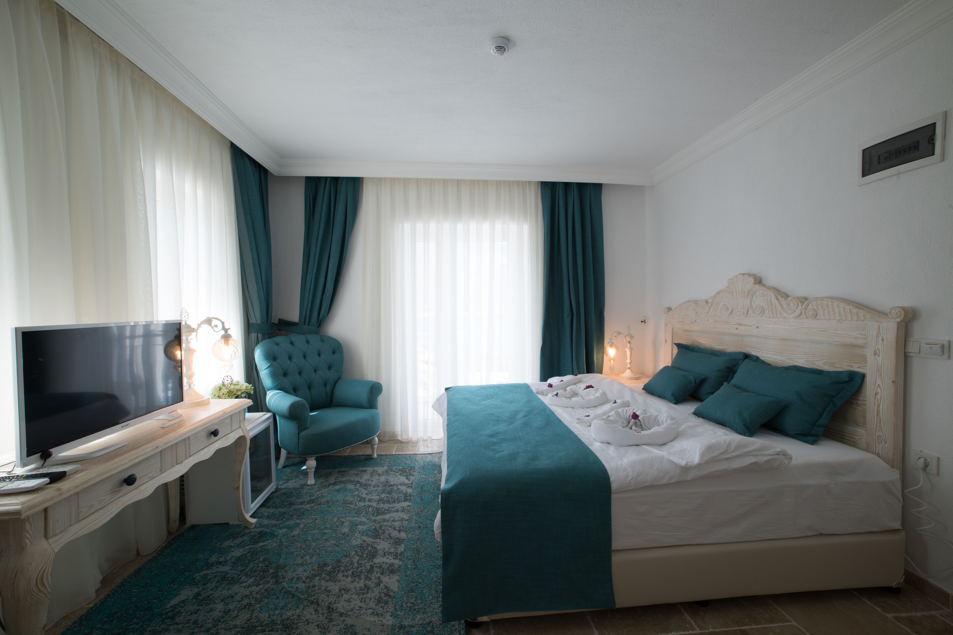 Habitació d'hotel amb un llit, televisió, escriptori i una cadira.