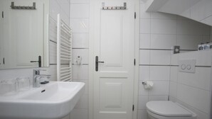 Een badkamer met een wit wastafelmeubel, spiegel en toilet.