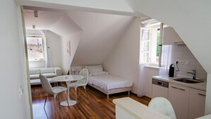 Een compact appartement in moderne stijl met een slaapkamer op entresol, een eethoek en een kitchenette.