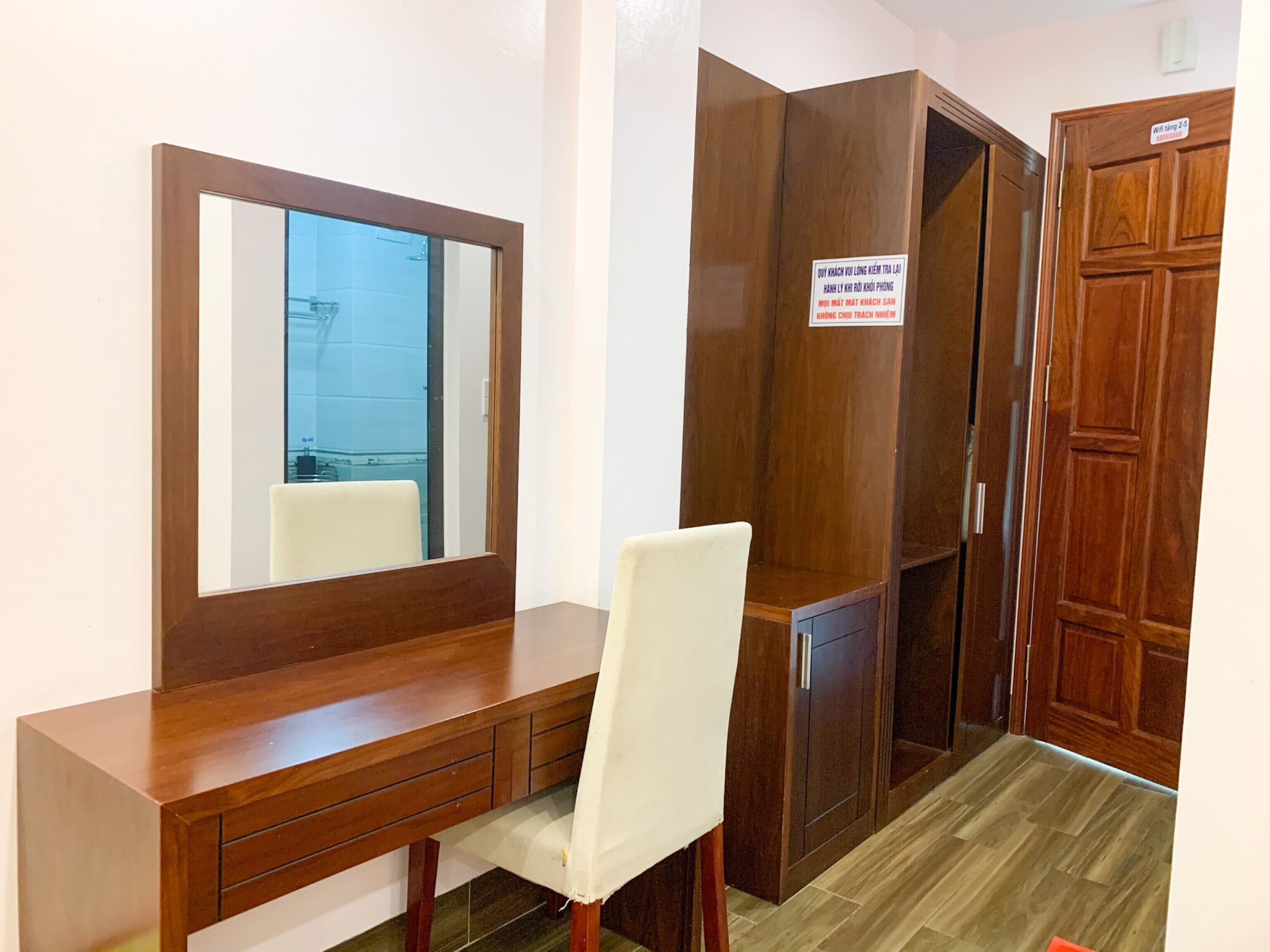 Une pièce comprenant un bureau en bois, une chaise, une armoire et un miroir.