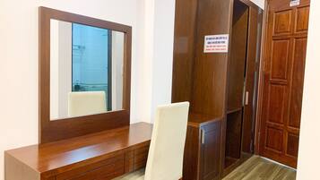 Une pièce comprenant un bureau en bois, une chaise, une armoire et un miroir.
