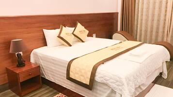 A neatly made bed with a wooden headboard, a bedside table with a lamp, and a floral-patterned rug.