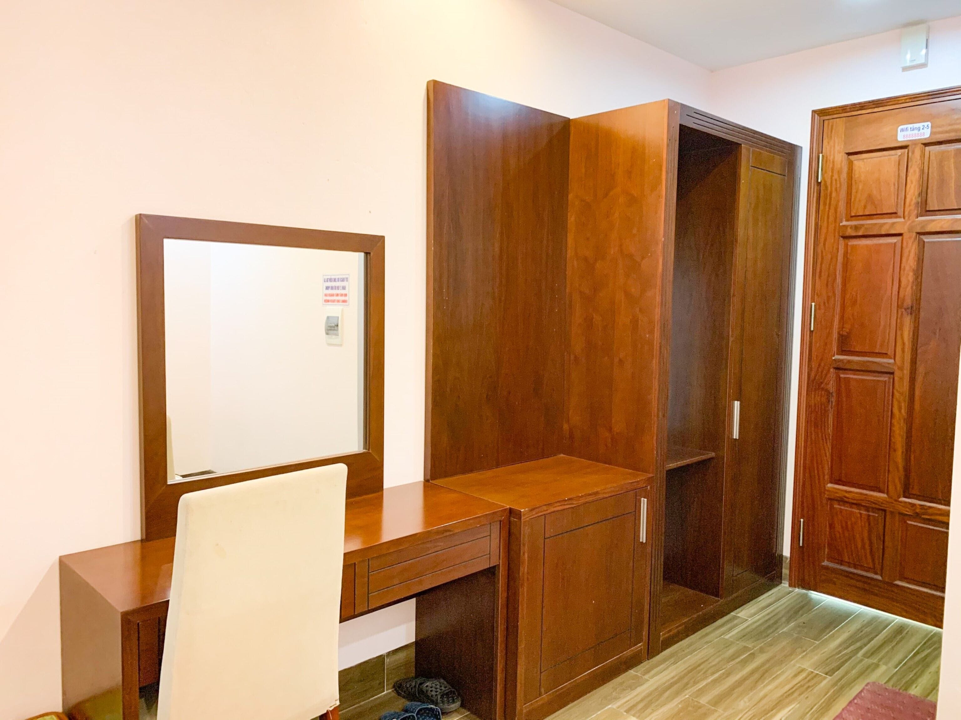 Una habitación con escritorio de madera, una silla y un armario.