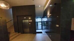 Un vestíbulo moderno con una escalera, un mostrador de recepción y una entrada con puerta de cristal.