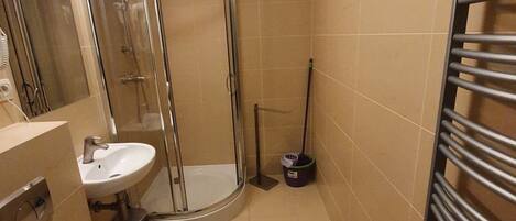 A bathroom with a shower, two sinks, a toilet, and a towel rack.