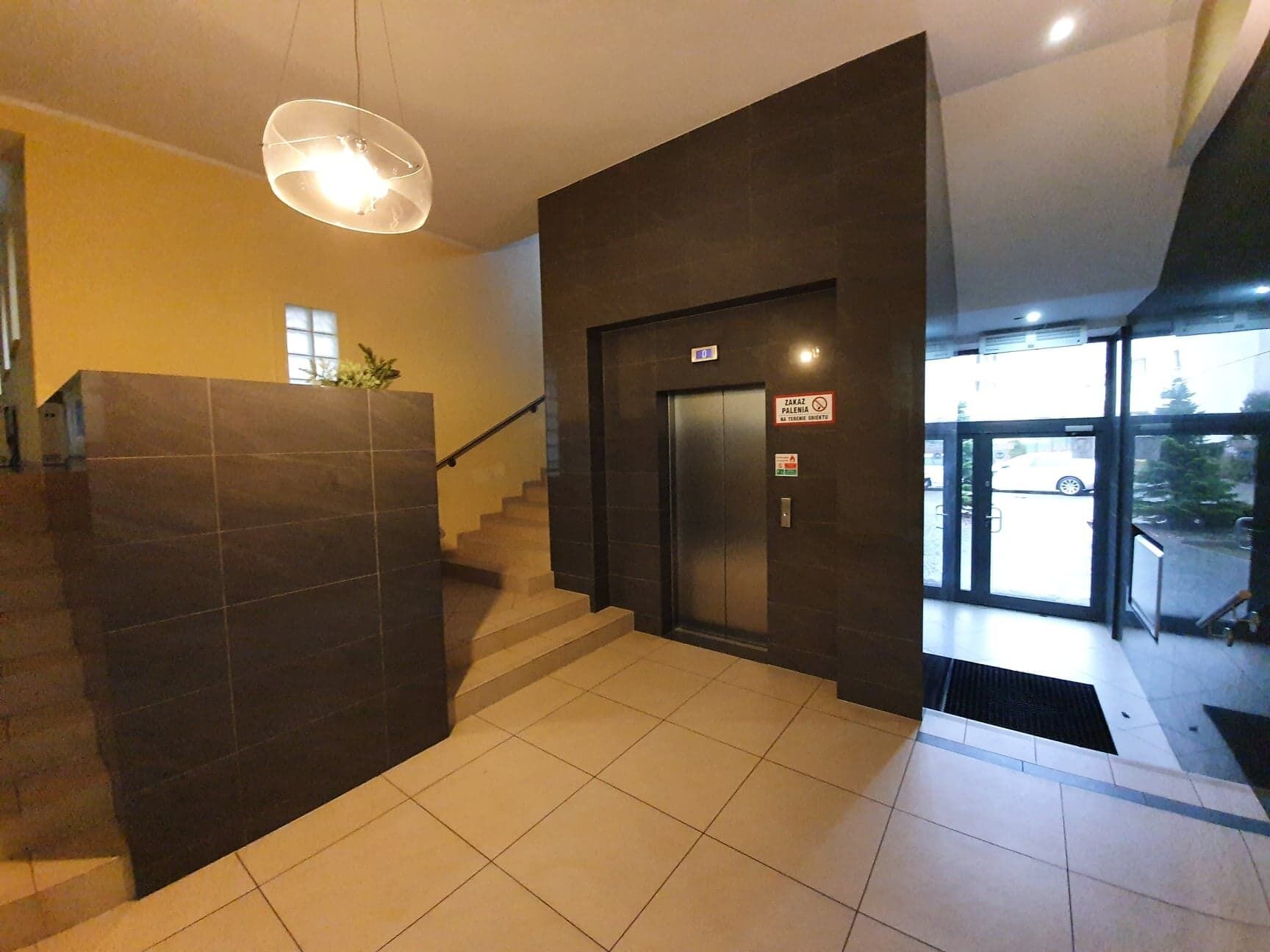 A modern interior with a staircase, a reception area, and a glass door leading outside.