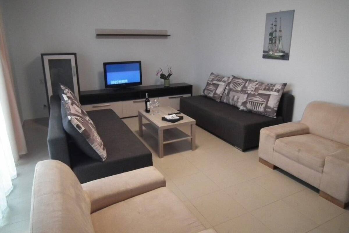 Uma sala de estar moderna com televisão de tela plana, dois sofás, uma mesa de centro e uma mesinha lateral.