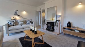 A modern living room with a grey sofa, a black fireplace, and a wooden coffee table. - Beech Dreams - Stylish Place to Stay (Conwy)