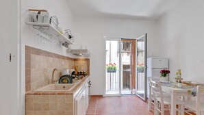 A kitchen with a tiled backsplash, a sink, a stove, and a dining area with a table and chairs. - GuestHost - Cozy 60 sqm apartment, for 3 people, with 3 balconies and located on the 2nd floor of a renovated building without lift. The property is located in the heart of the historic center (Traffic Restricted Area), inside Vucciria area, one of the c (Palermo)
