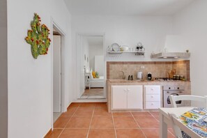 A kitchen with white cabinets, a tiled backsplash, and a dining area with a table.
