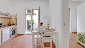 A kitchen with white cabinets, a stove, and a dining area with a table and chairs. - GuestHost - Cozy 60 sqm apartment, for 3 people, with 3 balconies and located on the 2nd floor of a renovated building without lift. The property is located in the heart of the historic center (Traffic Restricted Area), inside Vucciria area, one of the c (Palermo)