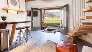 A modern kitchen with a wooden countertop, bar stools, and a stainless steel pot. - Clark Farm Silos #1 - Panoramic Mountain Views (Kalispell)