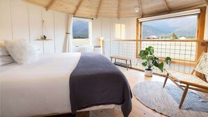 A bedroom with a large bed, a balcony with a view, and a wooden ceiling. - Clark Farm Silos #2 - Incredible  Mountain Views (Kalispell)