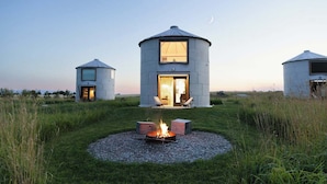A yurt-style building with a fire pit in the center, surrounded by a grassy field. - Clark Farm Silos #4  - Scenic Mountain Views (Kalispell)