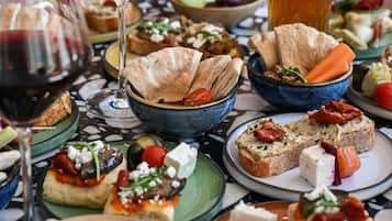 A table with various food items and drinks, including bread, cheese, and a glass of wine.