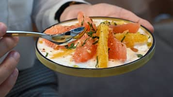 A person holding a bowl of food with a spoon.