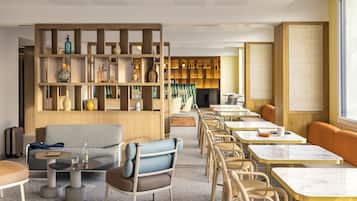 A modern hotel lobby with a seating area, a bar, and a large window.