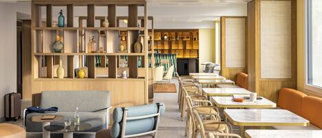 A modern hotel lobby with a seating area, a bar, and a large window.