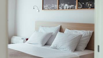Een hotelkamer met een bed, een nachtkastje met boeken en een aan de muur hangend beeld van een bergachtig landschap.
