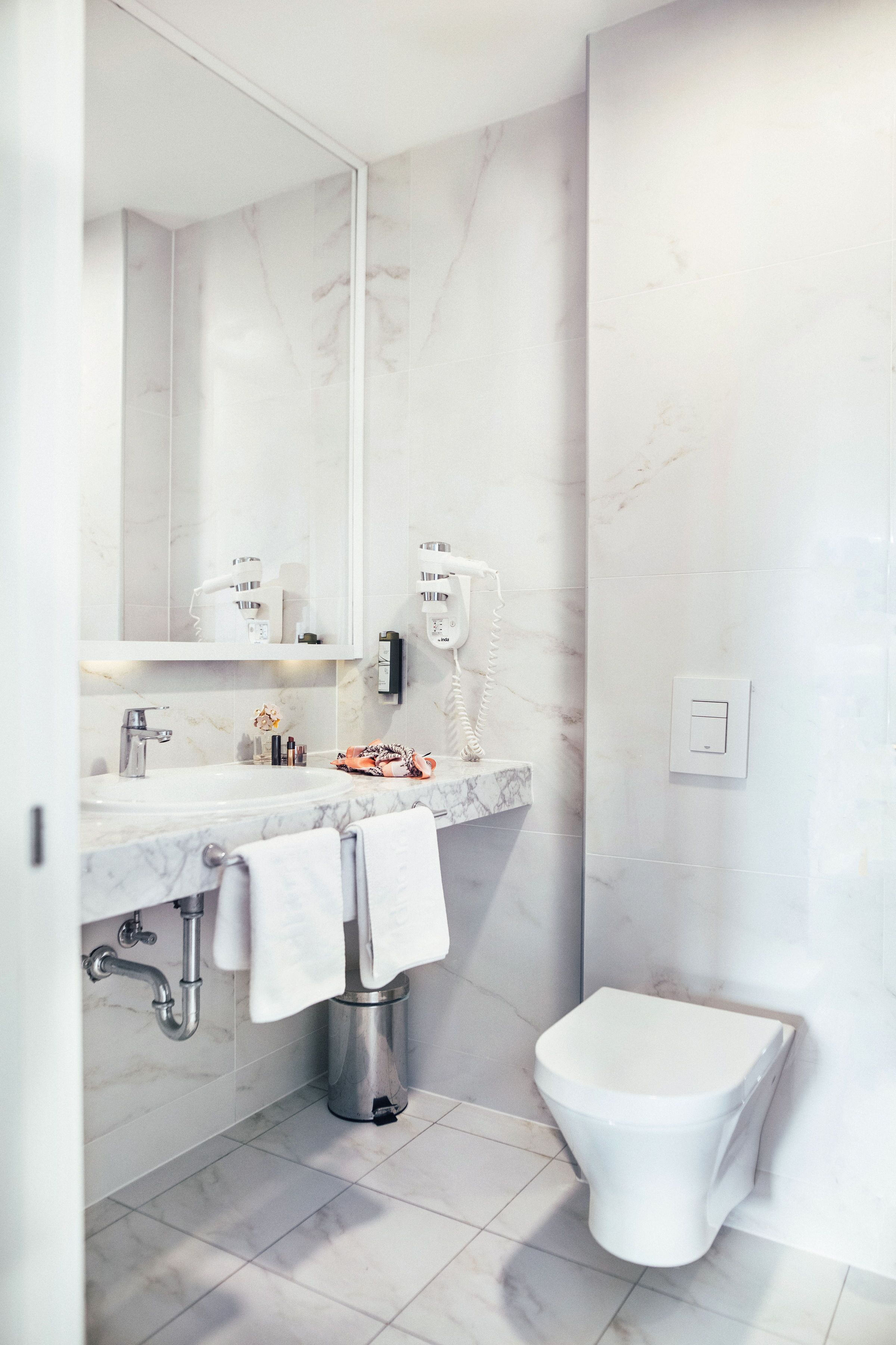 A modern bathroom with a marble sink, a toilet, and a mirror.
