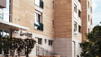 Un edificio moderno con fachada color beige, varios balcones y una escalera que conduce a la entrada.