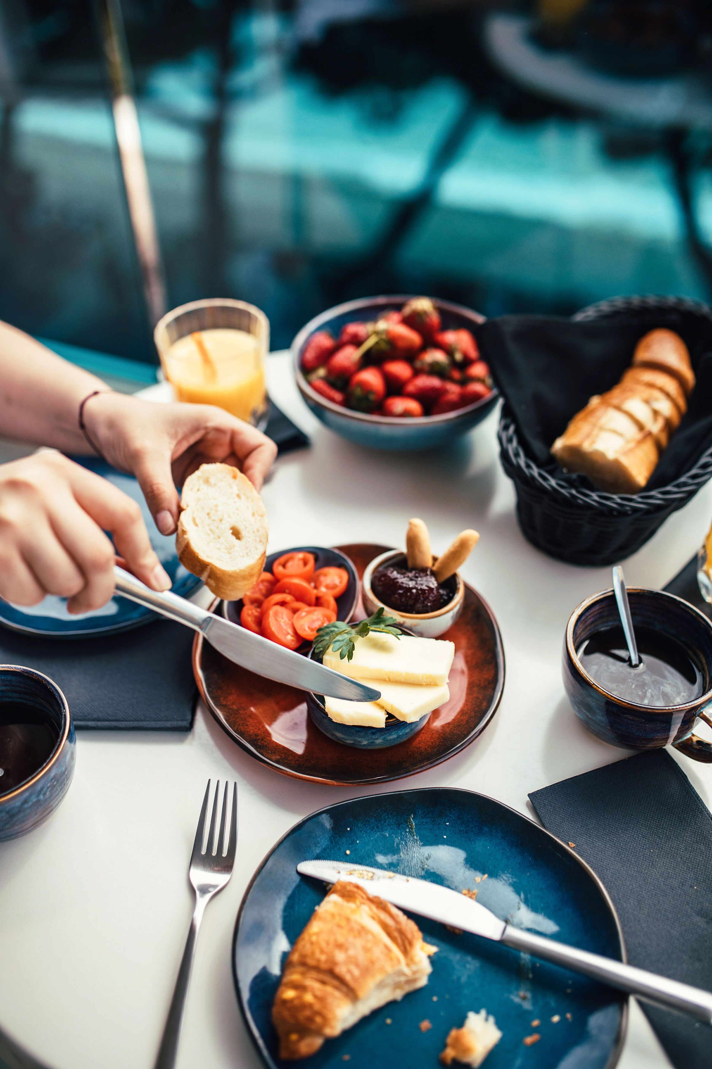 Een ontbijt met croissants, tomaten en een glas sinaasappelsap op een tafel.