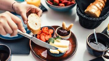 Een ontbijt met croissants, tomaten en een glas sinaasappelsap op een tafel.