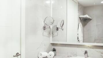 A modern bathroom with a marble vanity, a large mirror, and a shower area.