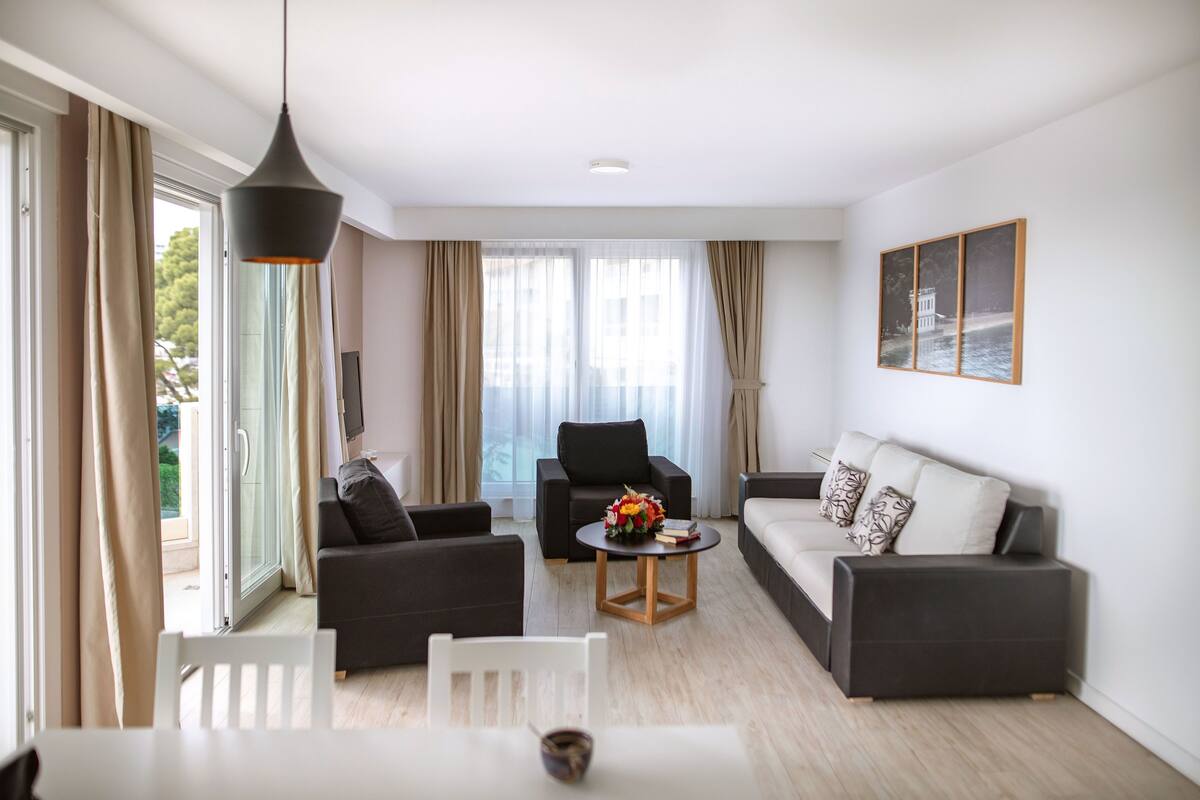 A modern living room with a sofa, armchairs, a coffee table, and a dining table.