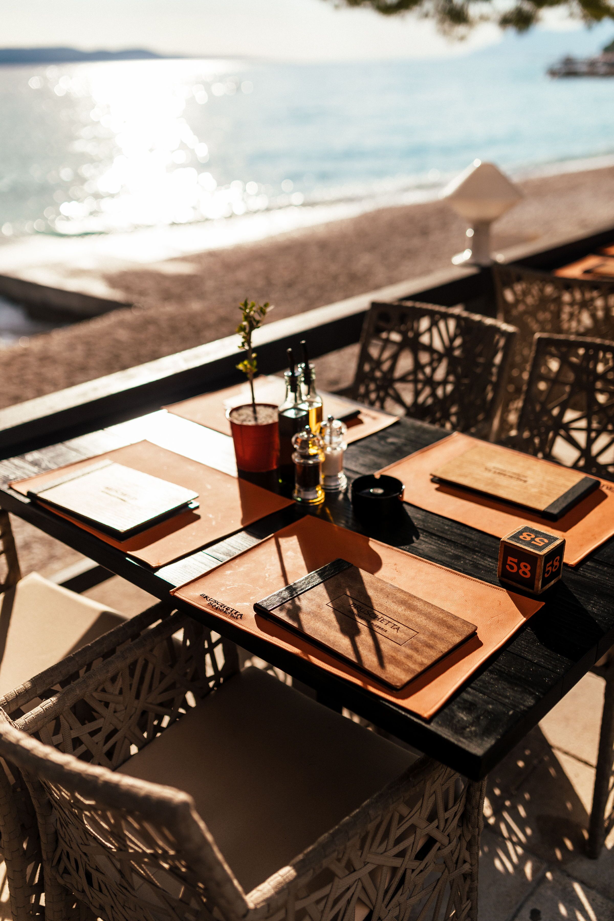 Mesa para dos con vistas a la playa, una botella de vino, una copa de vino tinto y un menú.