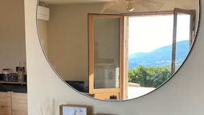 Un miroir rond posé sur une console, agrémentée de cadres avec des photos, d’un vase et d’une sculpture.
