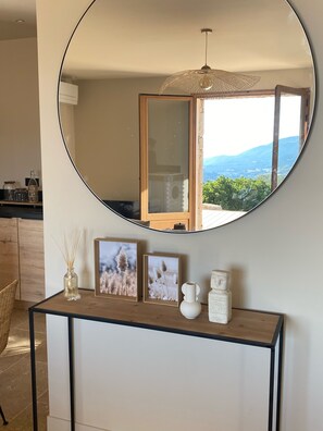 Een ronde spiegel op een console tafel, met ingelijste foto's, een vaas en een sculptuur.