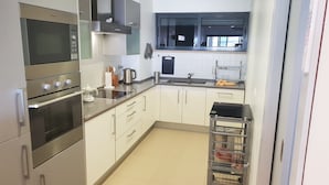 Une cuisine moderne dotée d’appareils électroménagers en acier inoxydable, de meubles blancs et d’une fenêtre située au-dessus de l’évier.